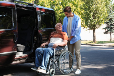 male caregiver assisting senior man that is sitting on the wheel chair