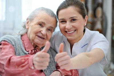 female caregiver and senior woman doing thumbs-up