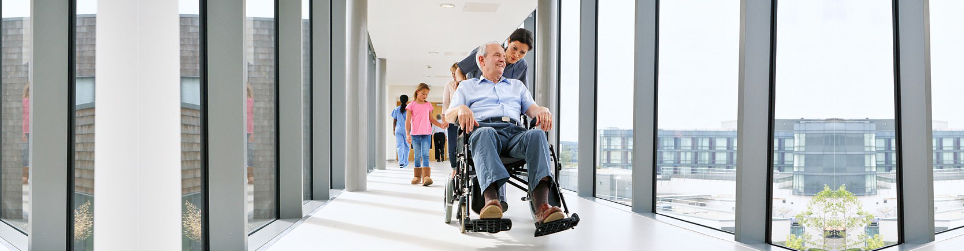 senior man on wheelchair accompanied by his caregiver